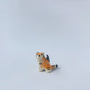 Very small glossy ceramic sculpture of a lion, sitting with a magpie on its back. The tiger has a carved poppy flower design on its back and gold detailing.