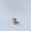 Very small glossy ceramic sculpture of a lion, sitting with a magpie on its back. The tiger has a carved poppy flower design on its back and gold detailing.