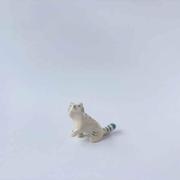 Very small glossy ceramic sculpture of a white tiger with blue stripes and subtle gold detailing.