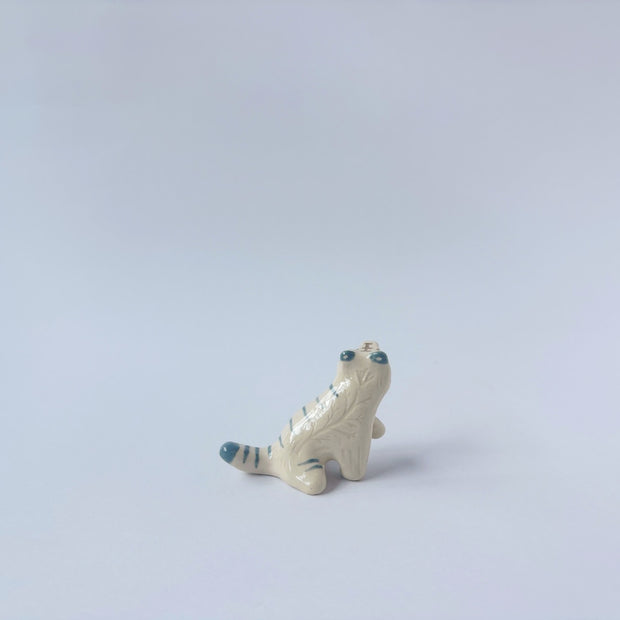Very small glossy ceramic sculpture of a white tiger with blue stripes and subtle gold detailing.