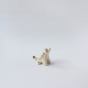 Very small glossy ceramic tiger sculpture, white with gold stripes and golden poppy flower design on its fur. It sits with a cute, happy expression.