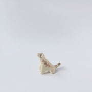 Very small glossy ceramic tiger sculpture, white with gold stripes and golden poppy flower design on its fur. It sits with a cute, happy expression.