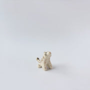 Very small glossy ceramic tiger sculpture, white with gold stripes and golden poppy flower design on its fur. It sits with a cute, happy expression.