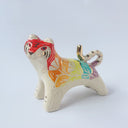 Glossy ceramic sculpture of a tiger with a white underbelly and rainbow coloring on its back with gold detailing.