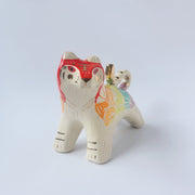 Glossy ceramic sculpture of a tiger with a white underbelly and rainbow coloring on its back with gold detailing.