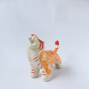 Glossy ceramic sculpture of a tiger with a white underbelly and orange fur with red stripes, gold detailing and white carved poppy flowers. It is in a roaring stance.