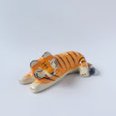 Glossy ceramic sculpture of a tiger, laying down asleep. It has a carved poppy flower pattern and gold detailing.