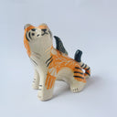 Glossy ceramic sculpture of a lion, sitting with a magpie on its back. The tiger has a carved poppy flower design on its back and gold detailing.