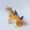 Glossy ceramic sculpture of a lion, sitting with a magpie on its back. The tiger has a carved poppy flower design on its back and gold detailing.