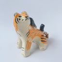 Glossy ceramic sculpture of a lion, sitting with a magpie on its back. The tiger has a carved poppy flower design on its back and gold detailing.