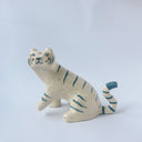 Glossy ceramic sculpture of a white tiger with blue stripes and subtle gold detailing.