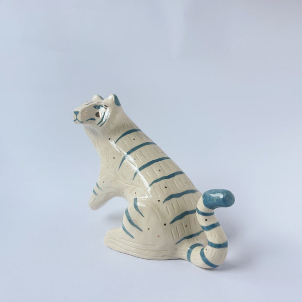 Glossy ceramic sculpture of a white tiger with blue stripes and subtle gold detailing.