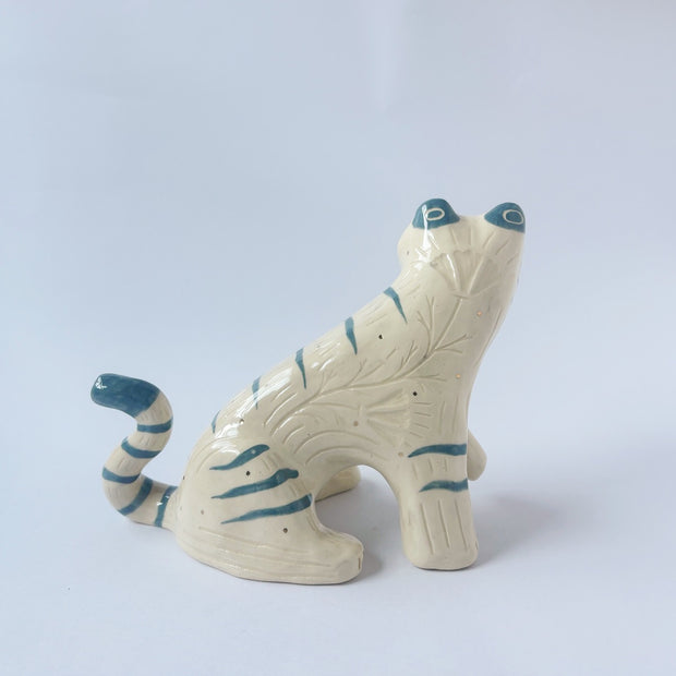 Glossy ceramic sculpture of a white tiger with blue stripes and subtle gold detailing.