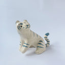 Glossy ceramic sculpture of a white tiger with blue stripes and subtle gold detailing.