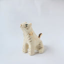 Glossy ceramic tiger sculpture, white with gold stripes and golden poppy flower design on its fur. It sits with a cute, happy expression.