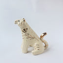 Glossy ceramic tiger sculpture, white with gold stripes and golden poppy flower design on its fur. It sits with a cute, happy expression.