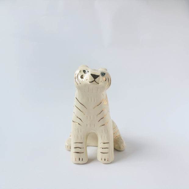 Glossy ceramic tiger sculpture, white with gold stripes and golden poppy flower design on its fur. It sits with a cute, happy expression.