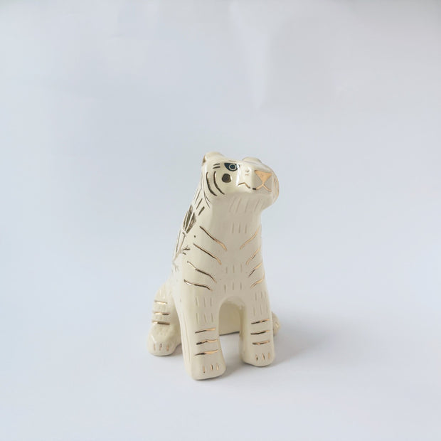 Glossy ceramic tiger sculpture, white with gold stripes and golden poppy flower design on its fur. It sits with a cute, happy expression.