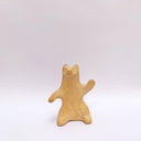 A brown clay sculpture of a bear, sitting on its hind legs, waving. It has subtle carved fur texture.