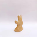 A brown clay sculpture of a bear, sitting on its hind legs, waving. It has subtle carved fur texture.