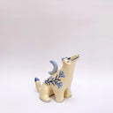 Cream colored ceramic sculpture of a wolf, with a blue crescent moon on its back and floral blue artwork on its body.