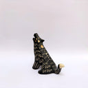 A black ceramic sculpture of a howling wolf with gold painted details and cream colored sgraffito fur details, set against a plain white background.