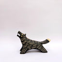 A black ceramic wolf figurine with cream colored sgraffito fur texture, it has 2 tails and howls upwards, with an open mouth.