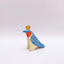 A ceramic bird sculpture with a natural cream colored clay body, blue wings and face detailing, red neck feathers, and a gold circular topper on its head, photographed on a clean light gray studio background.