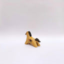 A small ceramic horse figurine in its natural brown clay coloring, decorated with black painted stripes on its mane and tail, and a circular multicolor emblem on its side, set against a plain light gray background.
