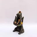 Ceramic figurine of a black bear, with its arms cradling 2 small animals - a miniature deer and a miniature buffalo. The bear has 2 ravens on its shoulders and a gold coin atop its head.