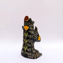 Ceramic figurine of a black bear, with its arms cradling 2 small animals - a miniature deer and a miniature buffalo. The bear has 2 ravens on its shoulders and a gold coin atop its head.