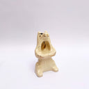 Cream colored ceramic sculpture of a bear, sitting on its hind legs with its arms cradled together. It has a recession in its chest where a gold star hangs. 