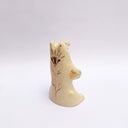 Cream colored ceramic sculpture of a bear, sitting on its hind legs with its arms cradled together. It has a recession in its chest where a gold star hangs. 