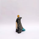 Ceramic sculpture of a black bird, with sgraffito wing patterning to reveal a cream colored clay, with blue and orange color detailing. It has a poppy flower on its back and a coin atop its head.