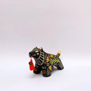 Ceramic sculpture of a black wolf/tiger like animal, on all fours with cream colored sgraffito detailing and poppy flower patterings on its body. It has a red tassel in its mouth.