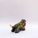 Ceramic sculpture of a black wolf/tiger like animal, on all fours with cream colored sgraffito detailing and poppy flower patterings on its body. It has a red tassel in its mouth.