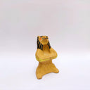 Beige ceramic sculpture of a lion/bear animal, sitting up on its hind legs, with its arms cradled together. There is a recession in its chest. It has subtle poppy flower designs on it.