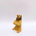 Beige ceramic sculpture of a lion/bear animal, sitting up on its hind legs, with its arms cradled together. There is a recession in its chest. It has subtle poppy flower designs on it.