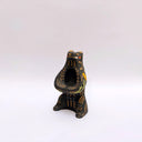 Black ceramic sculpture of a wolf/bear animal, sitting up on its hind legs, with its arms cradled together. There is a recession in its chest. It has subtle poppy flower designs on it.