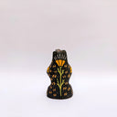 Black ceramic sculpture of a wolf/bear animal, sitting up on its hind legs, with its arms cradled together. There is a recession in its chest. It has subtle poppy flower designs on it.