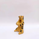 Beige ceramic sculpture of a wolf/tiger animal, sitting up on its hind legs, with its arms cradled together. There is a recession in its chest. It has subtle poppy flower designs on it.