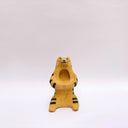 Beige ceramic sculpture of a wolf/tiger animal, sitting up on its hind legs, with its arms cradled together. There is a recession in its chest. It has subtle poppy flower designs on it.