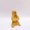 Beige ceramic sculpture of a wolf/bear animal, sitting up on its hind legs, with its arms cradled together. There is a recession in its chest. It has subtle poppy flower designs on it.