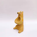 Beige ceramic sculpture of a wolf/bear animal, sitting up on its hind legs, with its arms cradled together. There is a recession in its chest. It has subtle poppy flower designs on it.