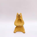 Beige ceramic sculpture of a wolf/bear animal, sitting up on its hind legs, with its arms cradled together. There is a recession in its chest. It has subtle poppy flower designs on it.