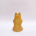 Beige ceramic sculpture of a wolf/bear animal, sitting up on its hind legs, with its arms cradled together. There is a recession in its chest. It has subtle poppy flower designs on it.