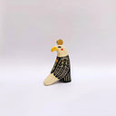 Ceramic sculpture of a bald eagle, looking to the side. Its wings are black and cream and it has a poppy flower art on its back. It has a gold coin atop its head.