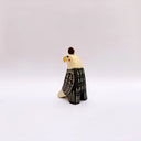 Ceramic sculpture of a bald eagle, looking to the side. Its wings are black and cream and it has a poppy flower art on its back. It has a gold coin atop its head.