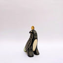 Ceramic sculpture of a black billed magpie, with stylized feather patterning in cream and mint green. On its back is a poppy flower and atop its head is a gold coin.