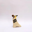 Cream colored ceramic sculpture of a bird, sitting in profile, with black and yellow feather detailings. It has a red cheek and a gold coin atop its head.